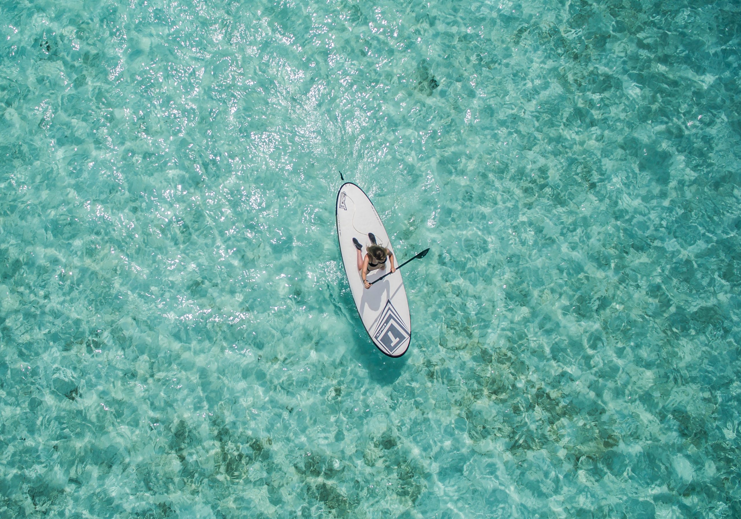 Picture of a woman paddling in the ocean and enjoying her slow travel experience